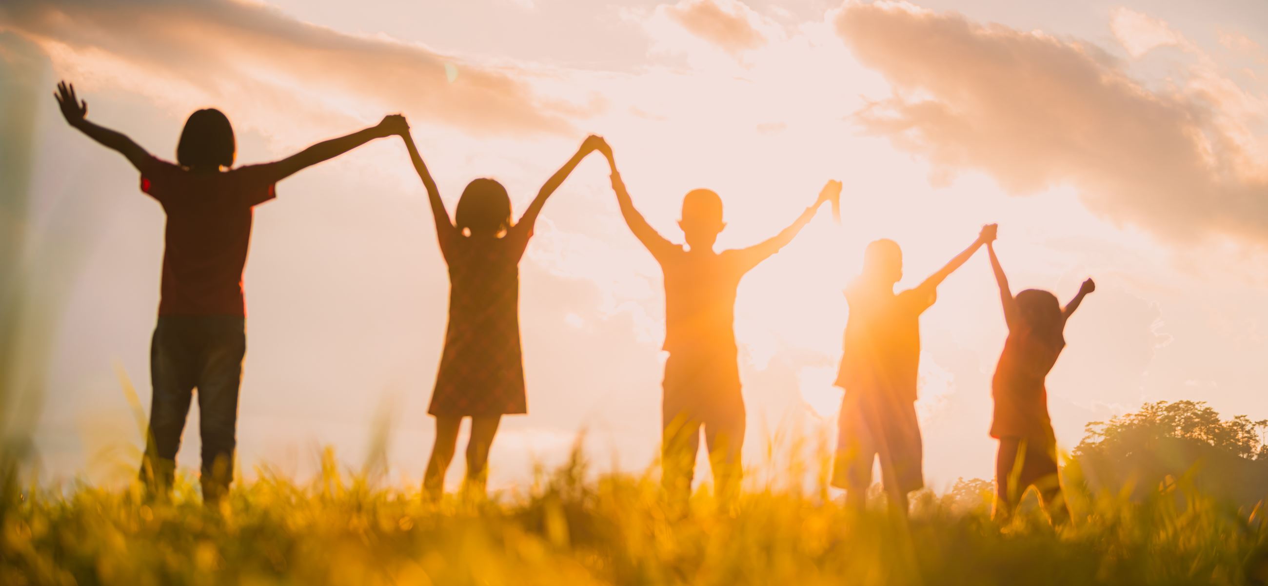 Line of children in silhouette jointly holding upraised hands